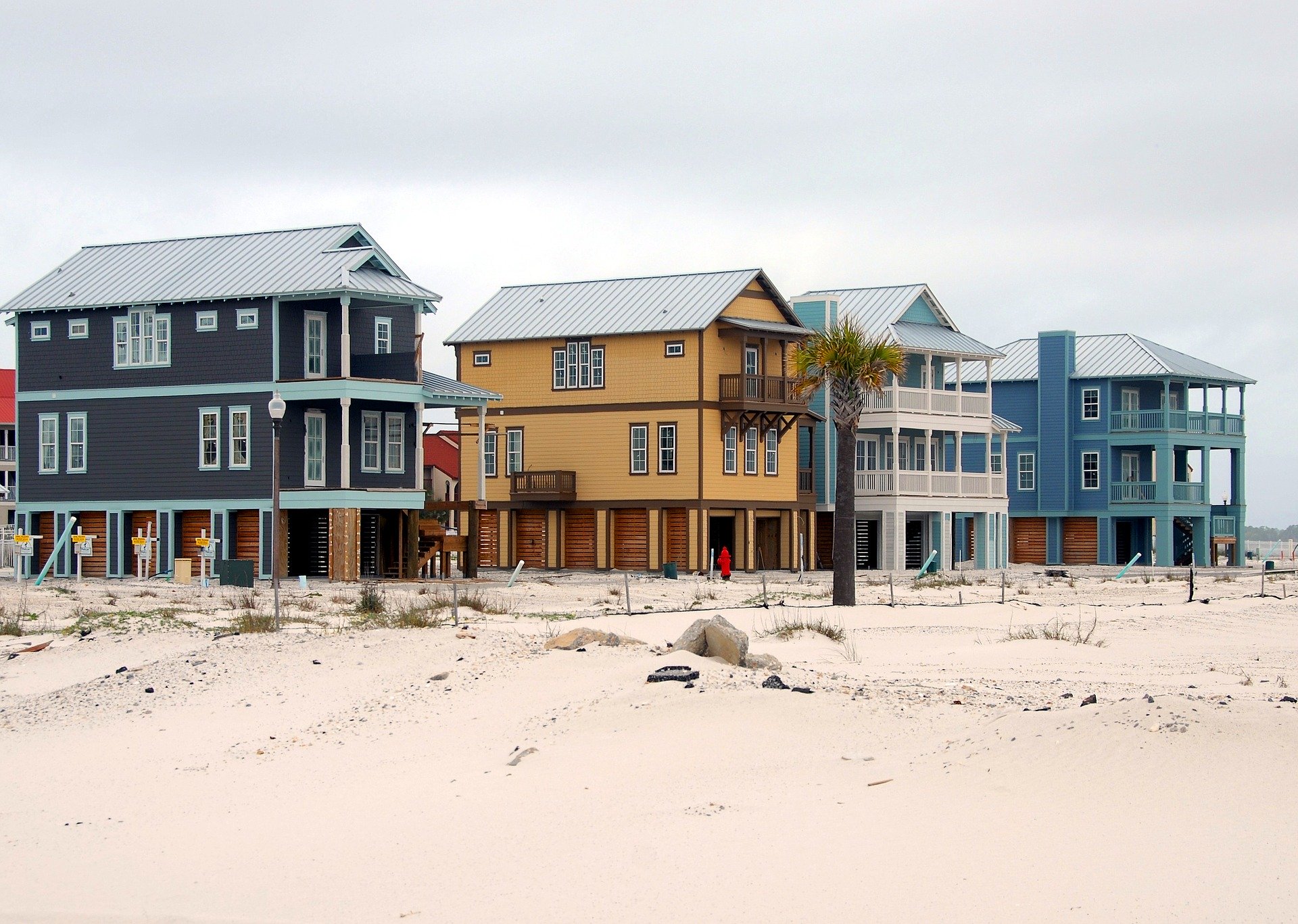 4 houses on the beach with sand and dunes representing why not to invest an IRA in real estate