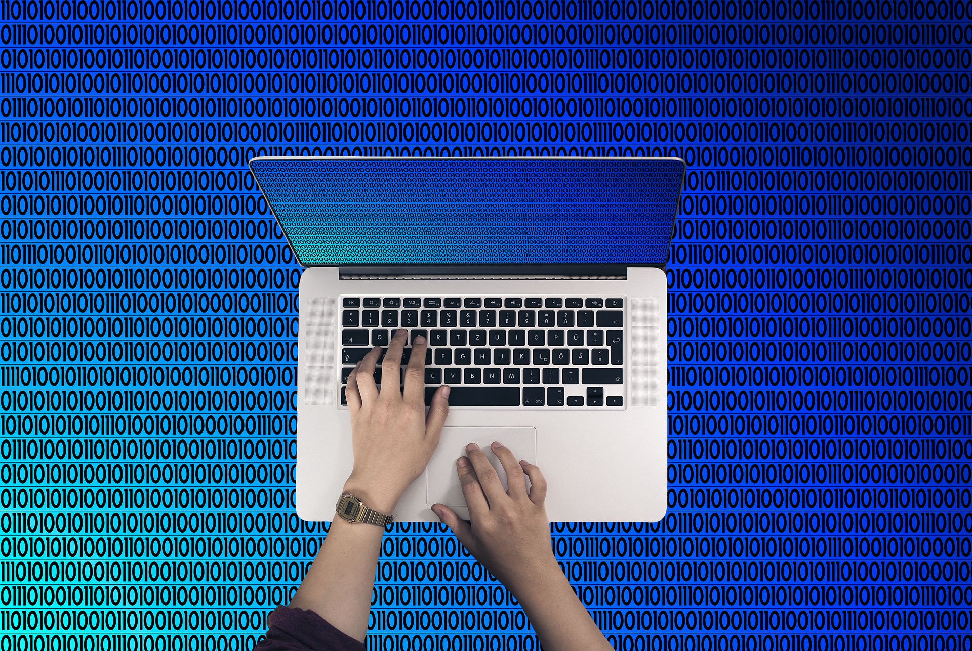 Woman typing on a laptop computer set against a blue computer binary grid