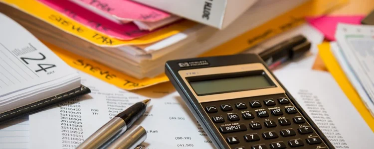 Income Tax Book Siting On Colorful Files With A Calculator, Pen And Paper