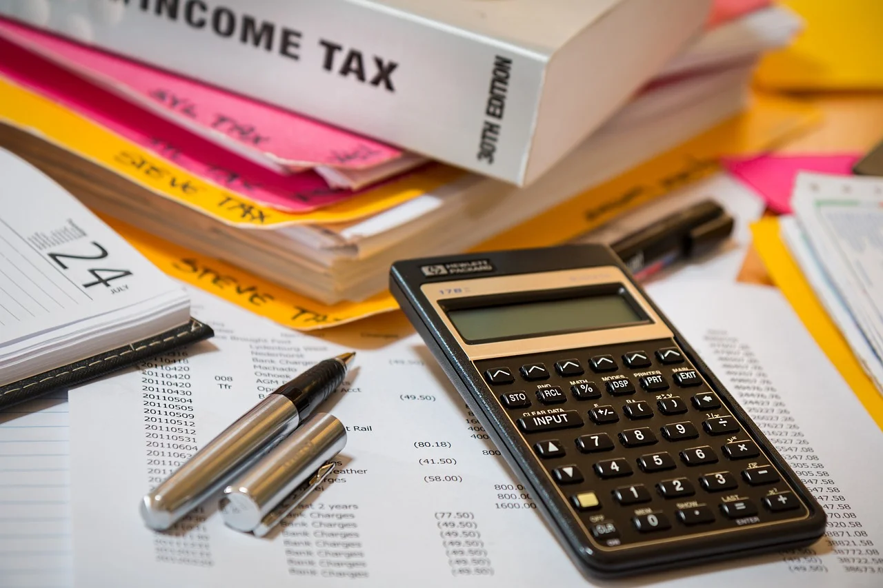 Income tax book siting on colorful files with a calculator, pen and paper